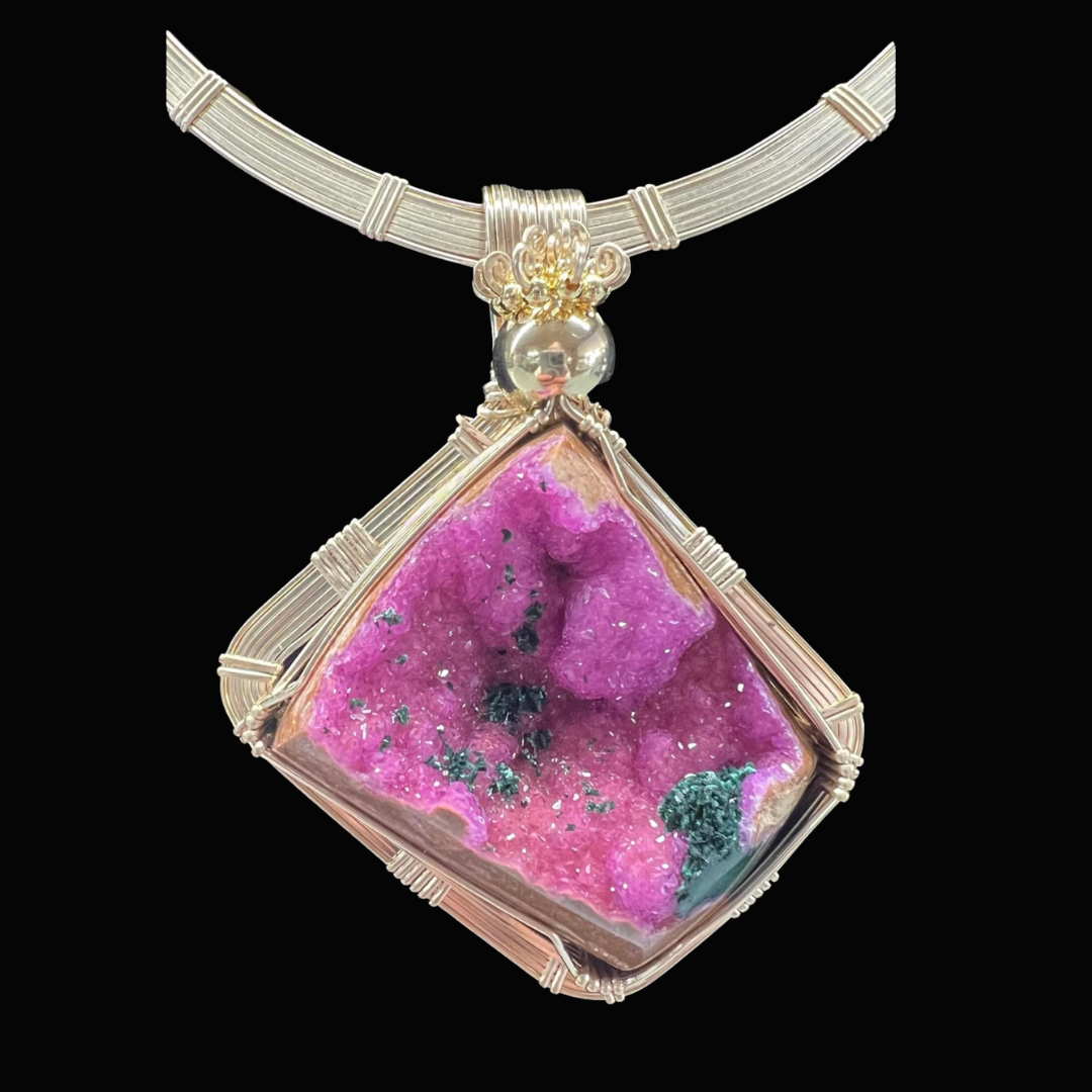 A necklace with a large, square, pink and black gemstone pendant wrapped in silver wire.