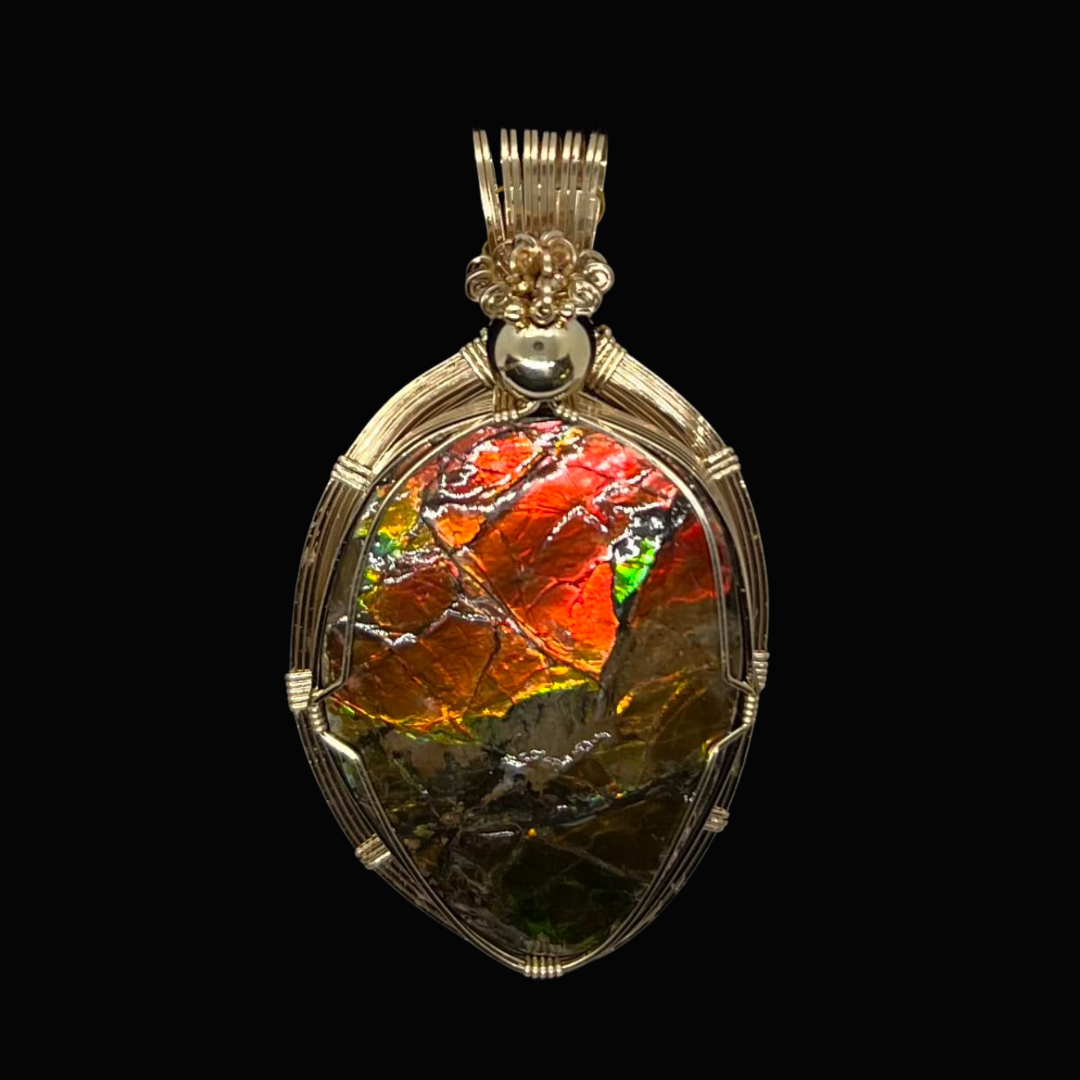 Gold pendant with an iridescent, multicolored leaf-shaped stone set inside a wire frame, against a black background.