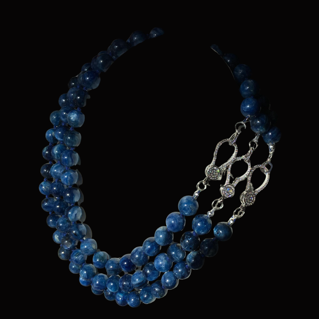 A three-strand necklace made of round, polished blue beads with silver clasp and decorative silver elements.