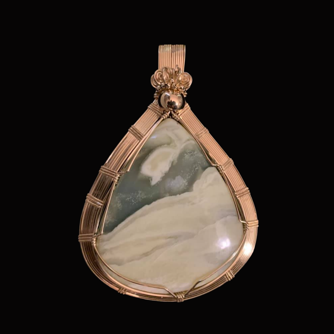 A teardrop-shaped pendant with a large central stone in shades of white and gray, encased in a gold wire setting with decorative elements at the top.