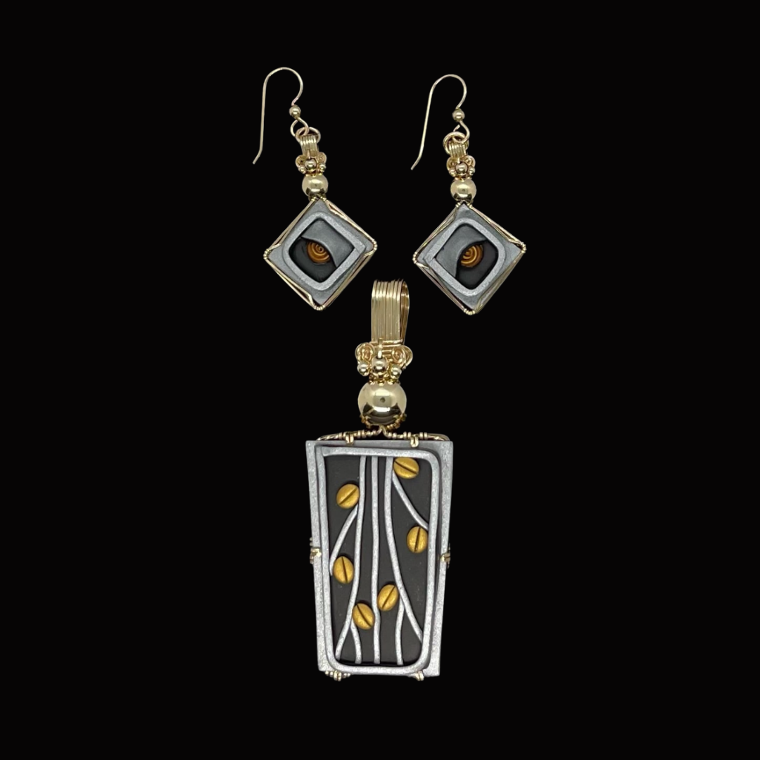 Jewelry set including a pair of earrings and a pendant necklace, featuring metallic black and gold accents with a tree and leaf design on a black background.