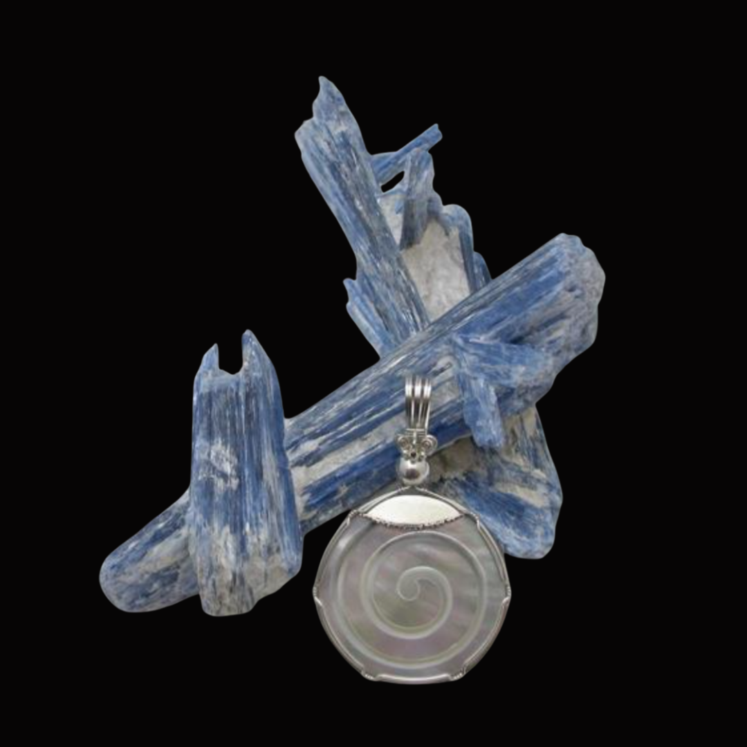 A silver pendant with a spiral design hangs in front of blue and white mineral crystals on a black background.