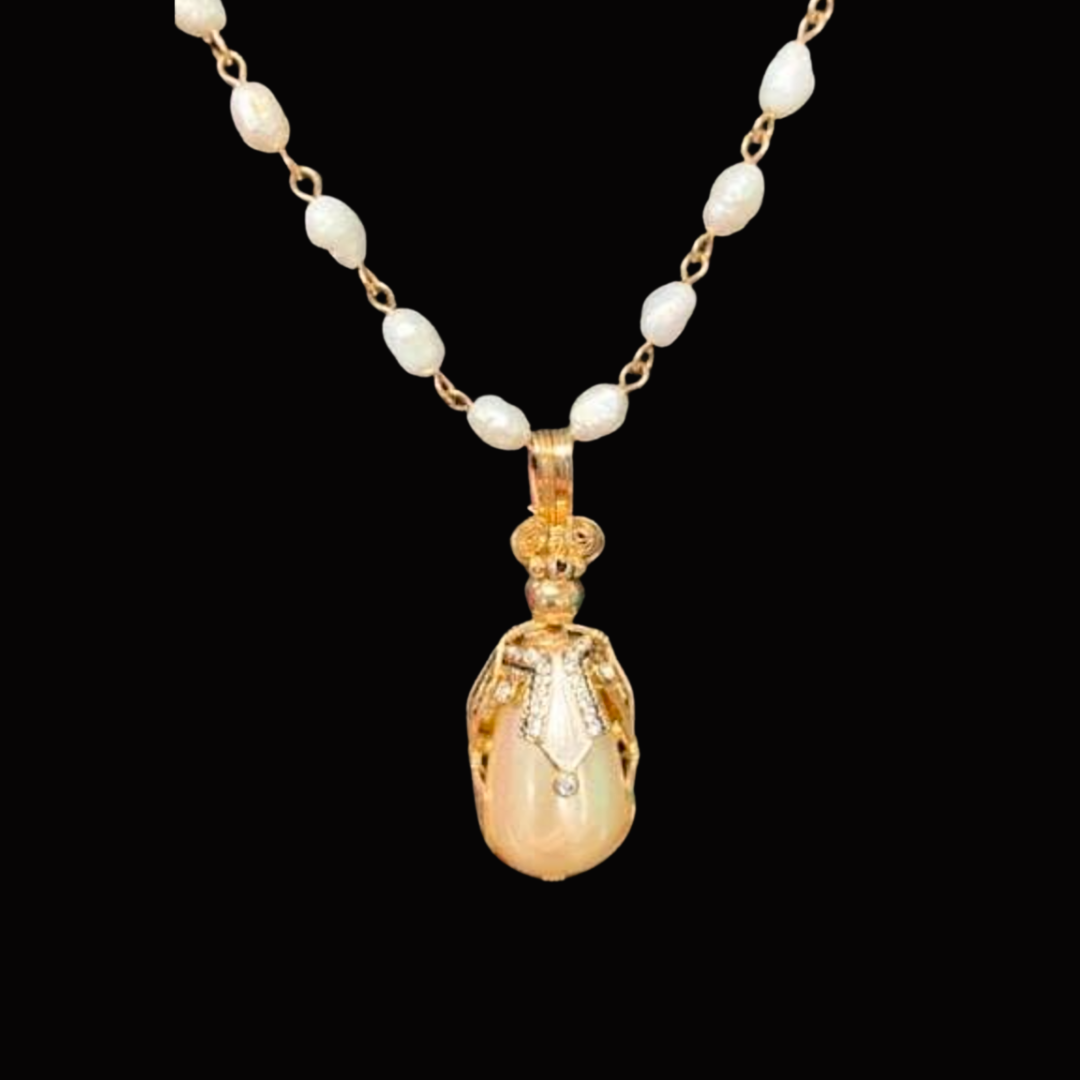 Pearl necklace with a large gold and pearl pendant against a black background.