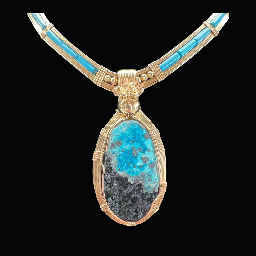 Gold necklace with rectangular turquoise inlays and a large oval turquoise pendant on a black background.