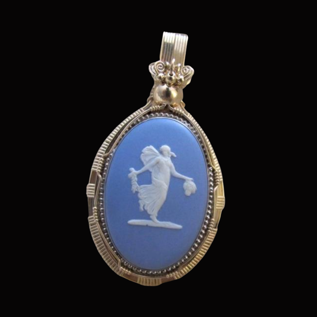 Gold pendant with light blue cameo featuring a white carved figure of a fairy holding objects, set against a black background.