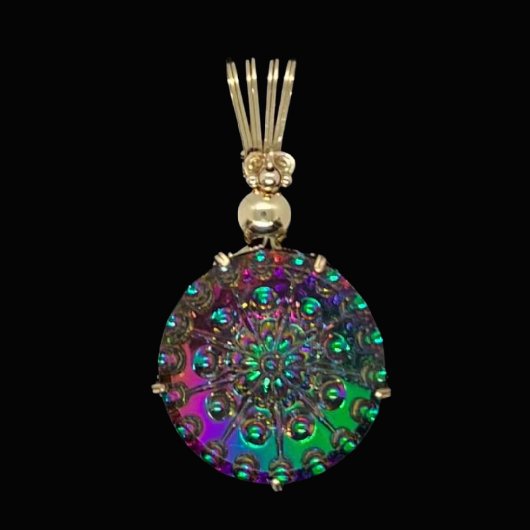 Colorful pendant with intricate pattern, set in gold, hanging from a decorative gold bail against a black background.