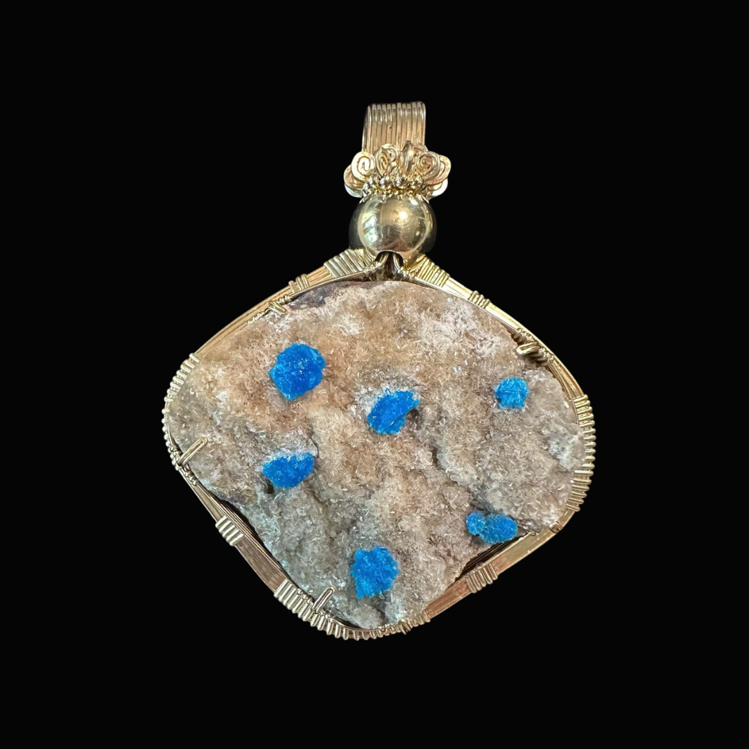Pendant with a large rough stone featuring blue mineral deposits, set in a gold wire frame with a decorative bail