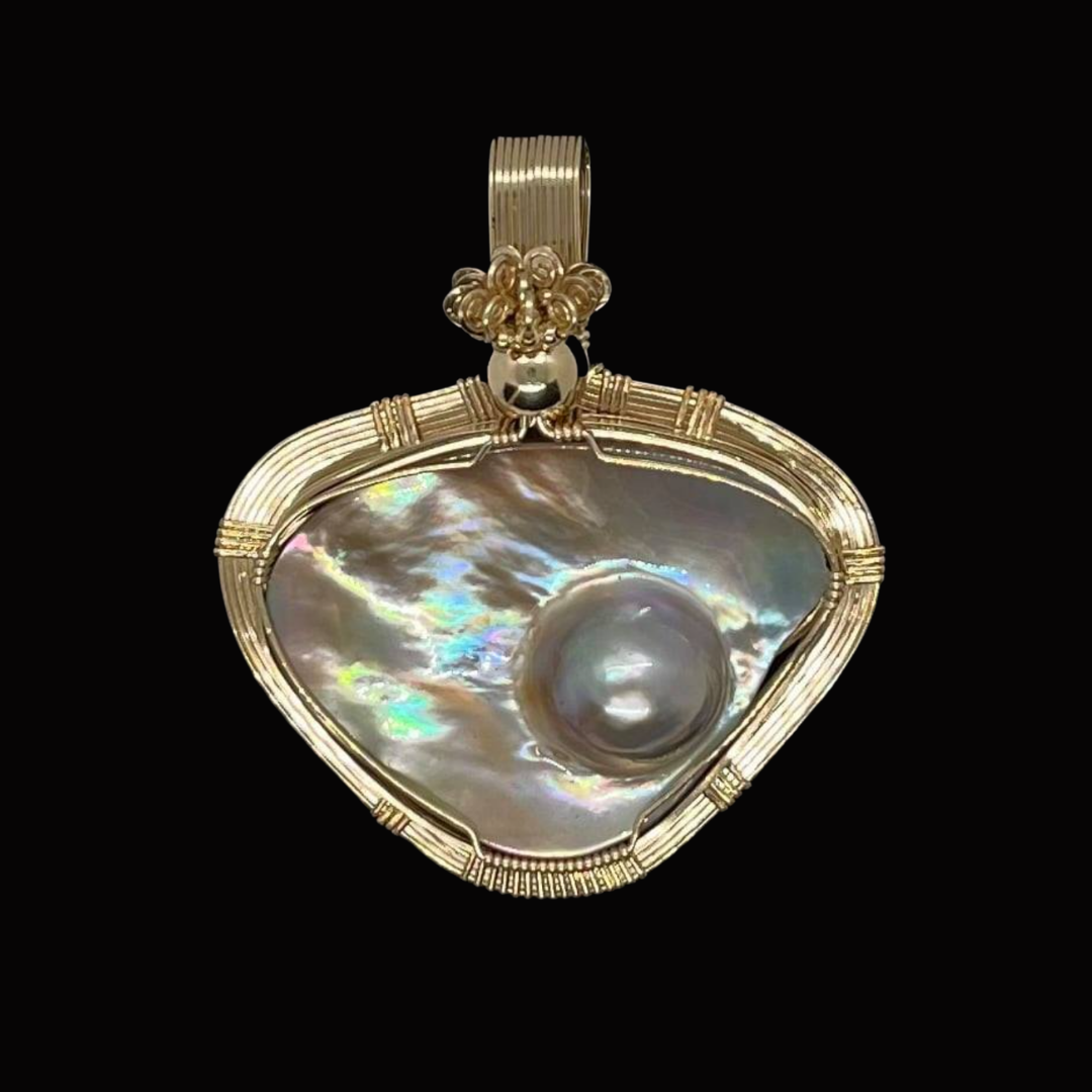 Pendant featuring a large, iridescent pearl set in a gold frame with intricate detailing.