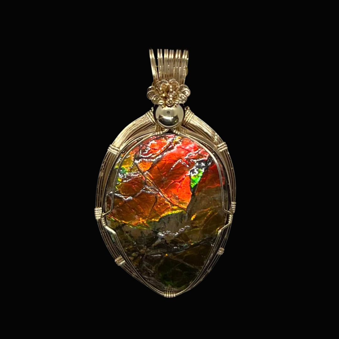Pendant with polished amber gemstone wrapped in silver wire on a black background.