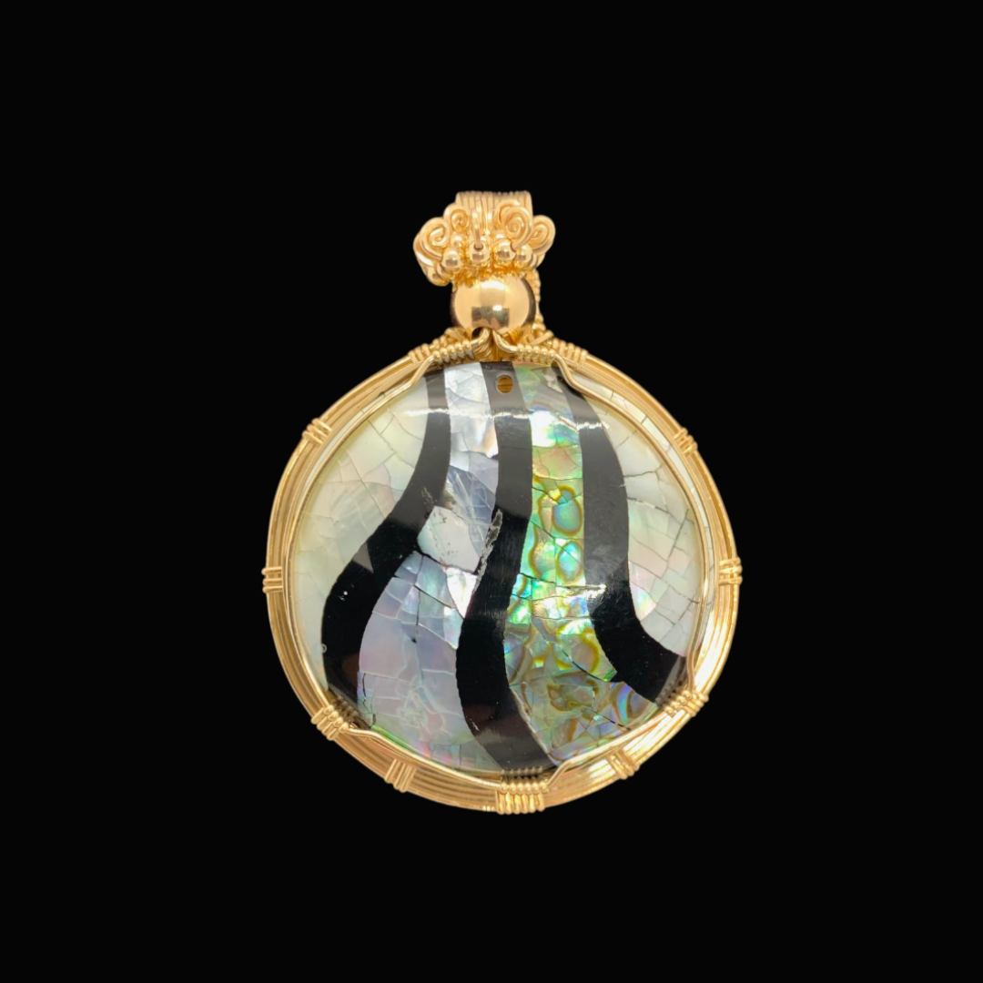 A round, ornate locket with black wavy lines and iridescent shell inlay, encased in a gold frame with intricate detailing, against a black background.
