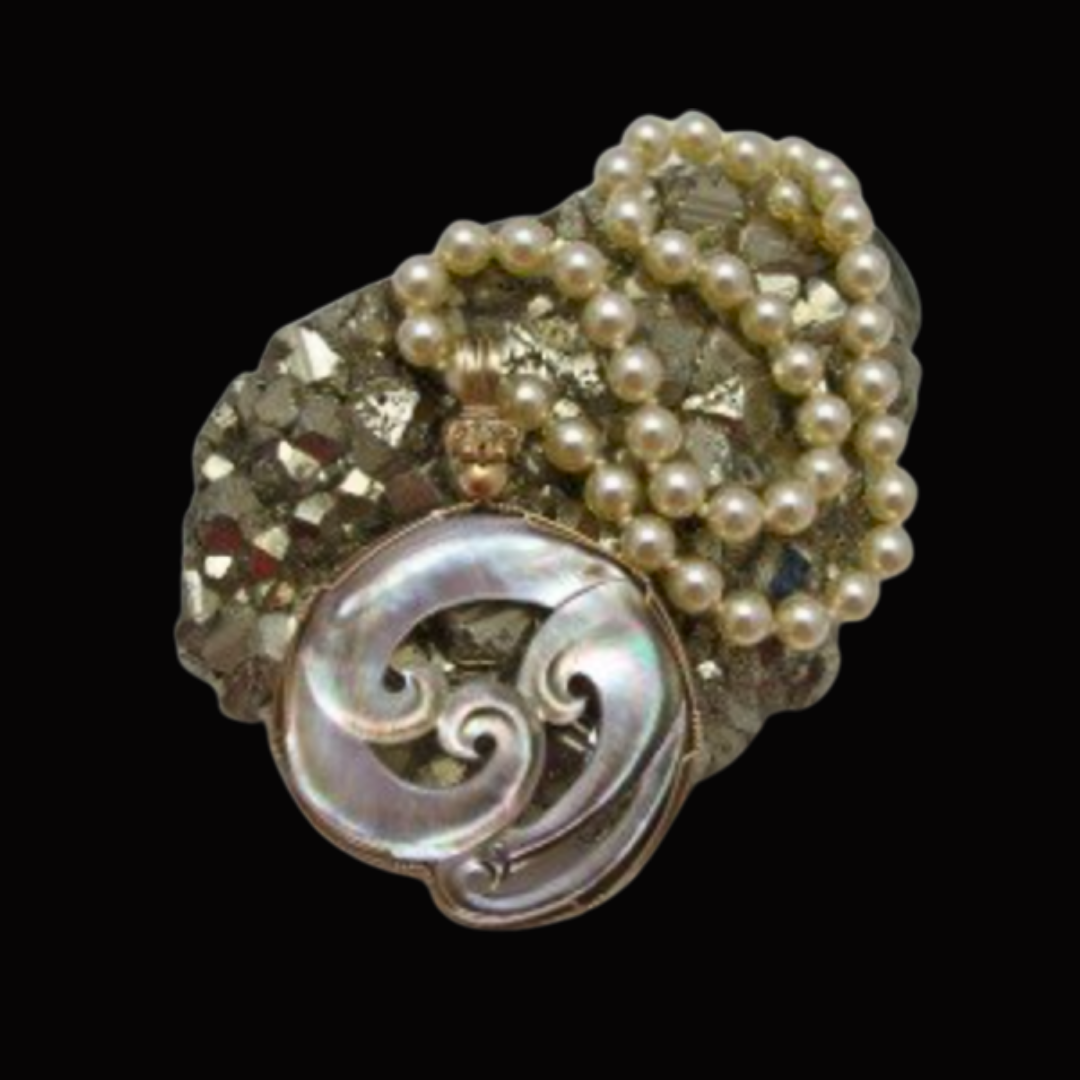 A cluster of pearl necklaces, a large decorative pearl, and a brooch with rhinestones on a black background.