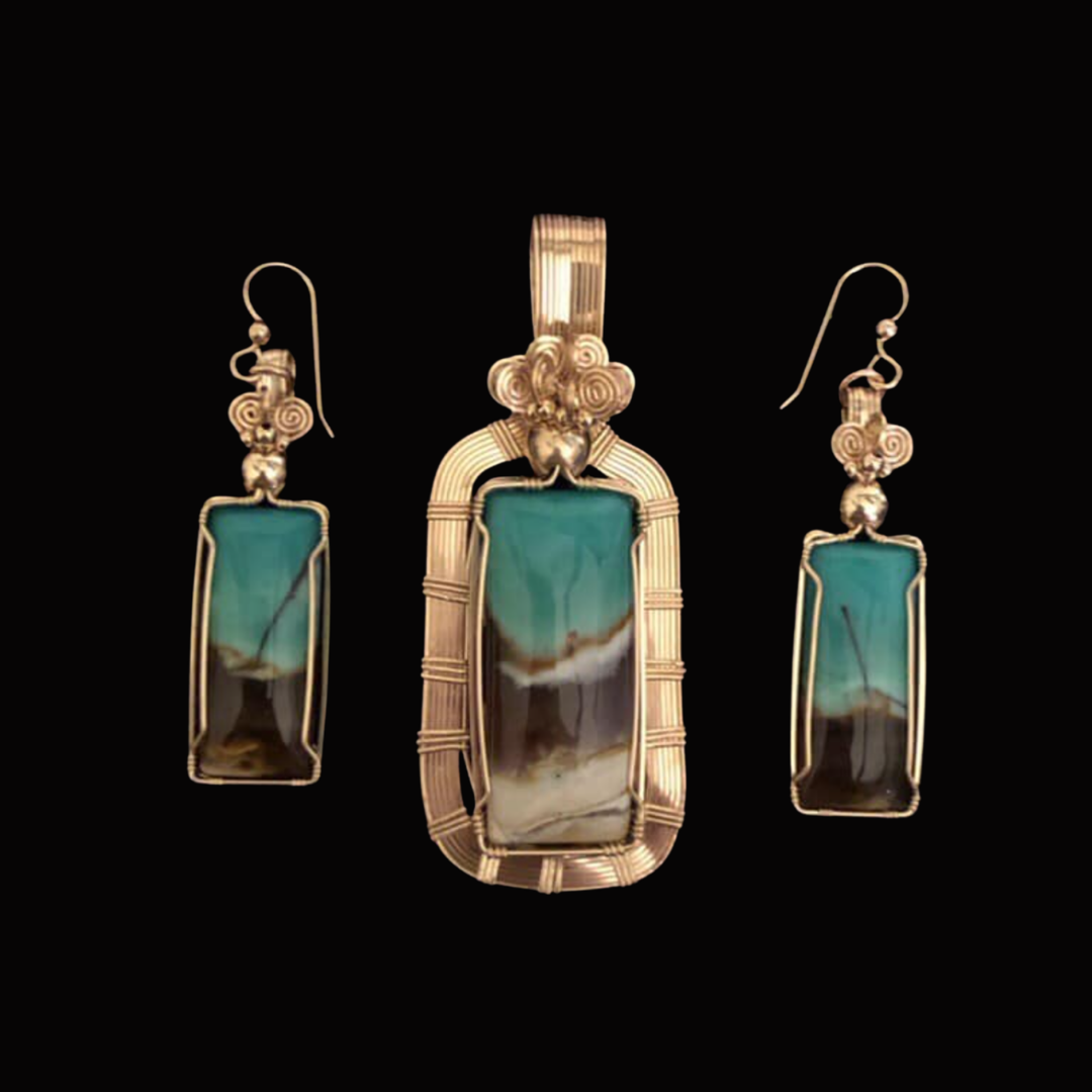 Set of turquoise and silver jewelry, including a pendant and matching earrings, with intricate wire wrapping and a black background.