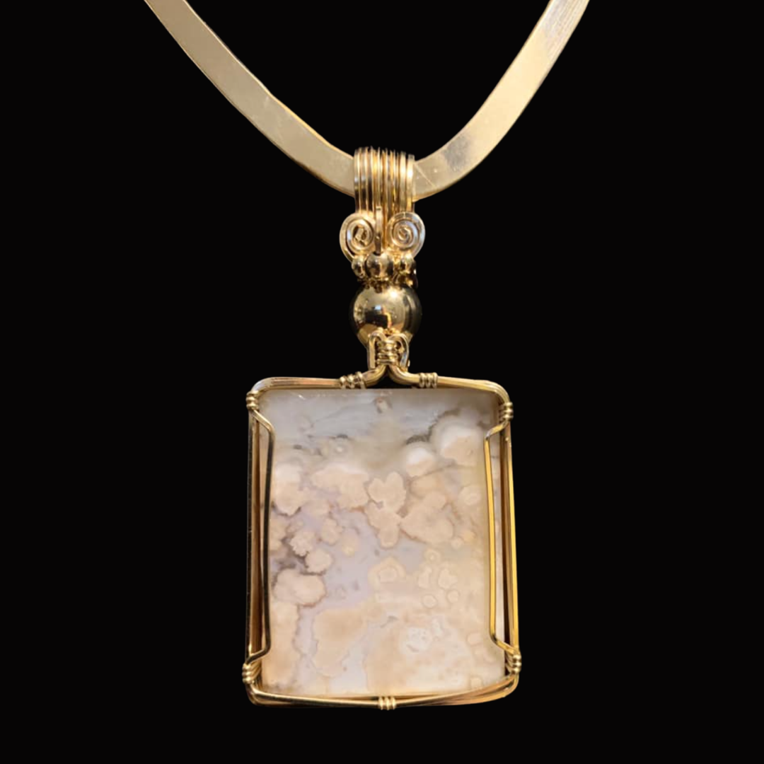 Gold necklace with a large rectangular pendant featuring a natural stone with beige and white patterns.