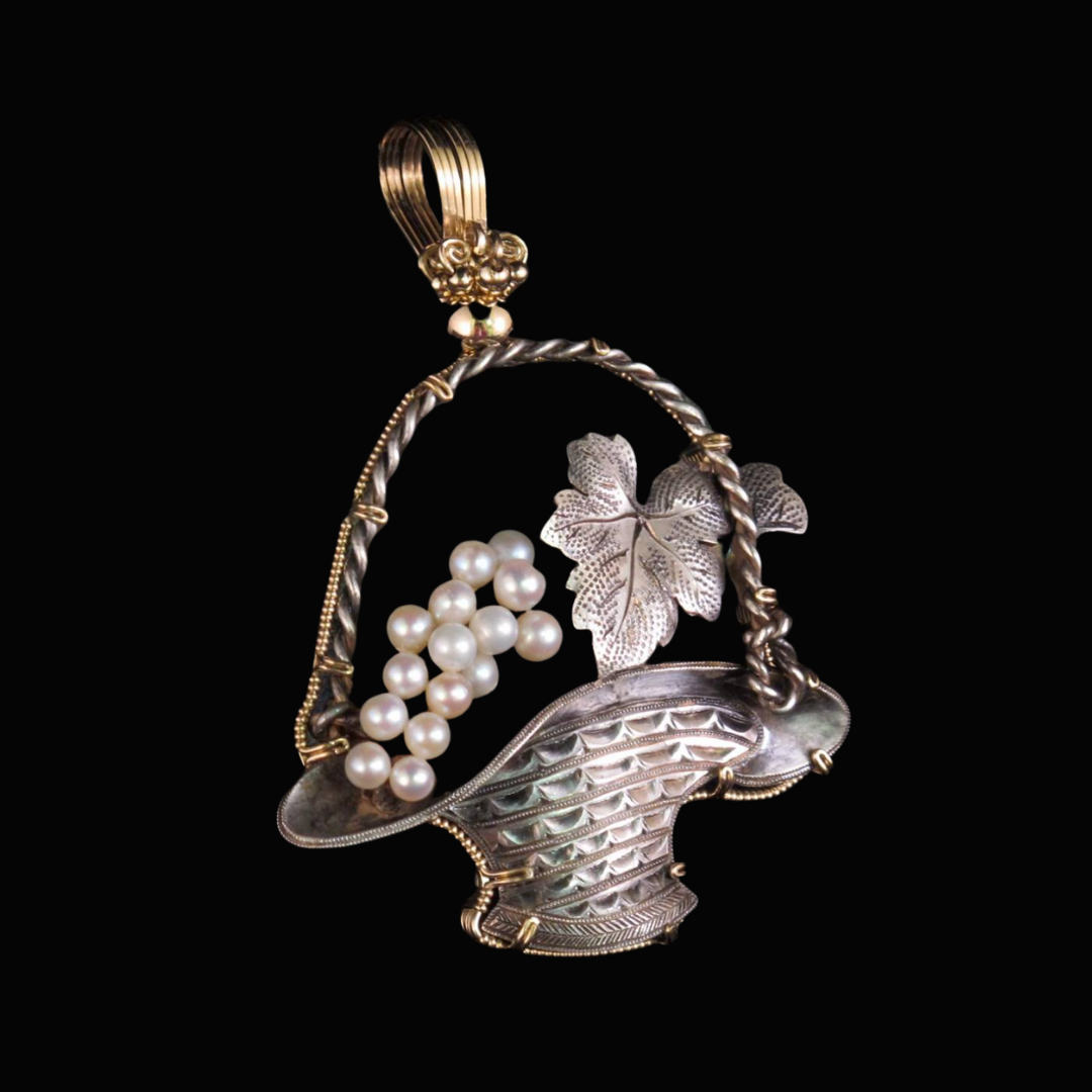 Silver jewelry pendant shaped like a basket with pearl-like beads and a leaf design, set against a black background.