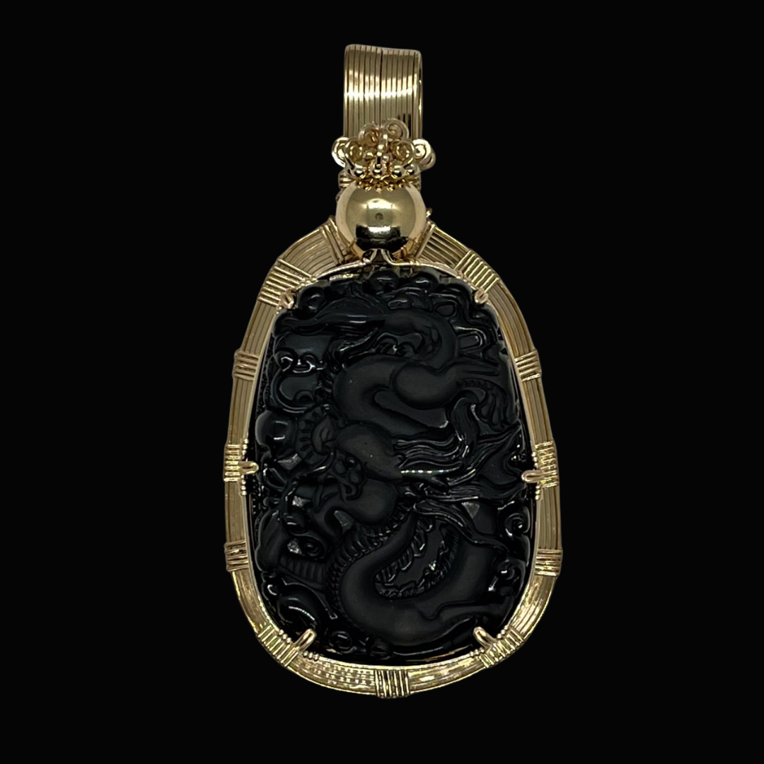 Gold pendant with intricately carved black jade dragon in the center, set against a black background.