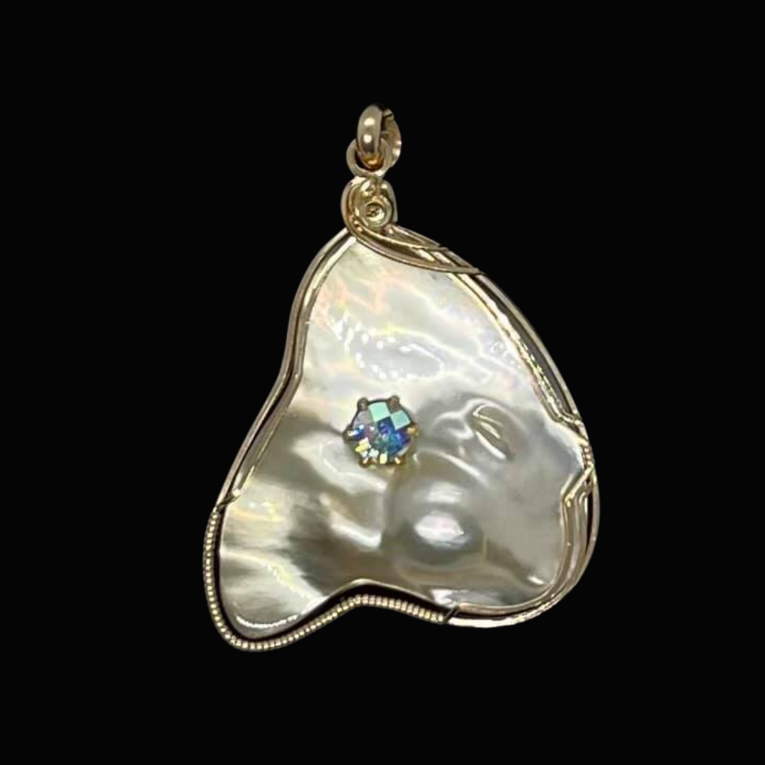 A pendant featuring a carved mother-of-pearl shell with a small diamond embedded, set in a gold setting against a black background.