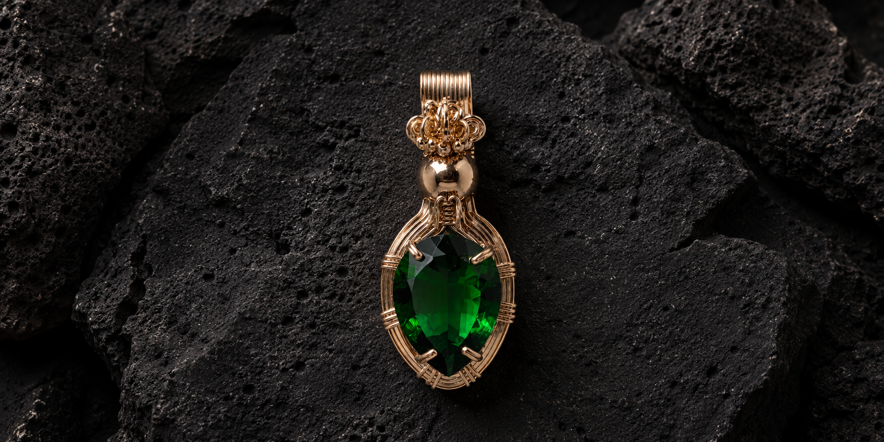 Gold pendant with large green gemstone on dark textured background.