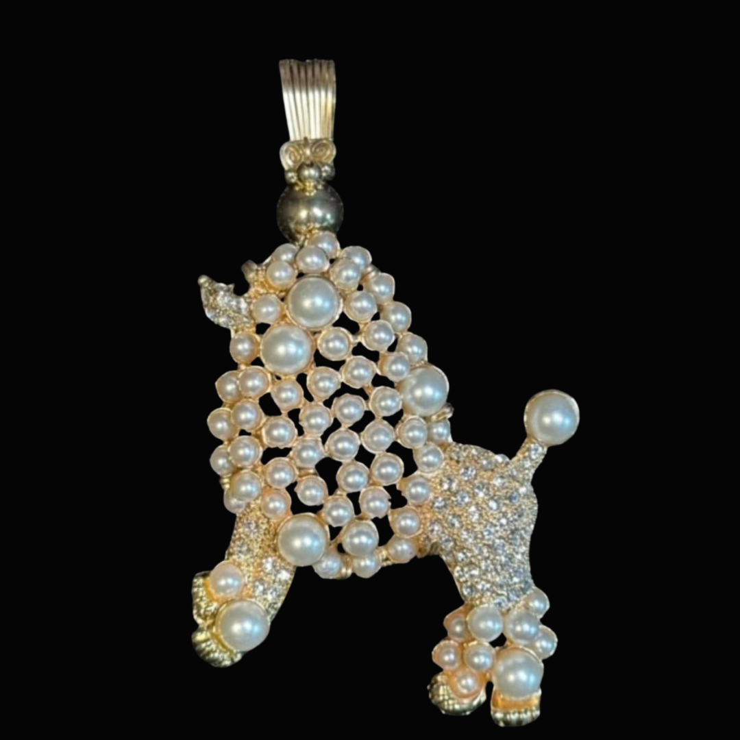 Poodle-shaped jewelry pendant decorated with pearls and small diamonds against a black background.