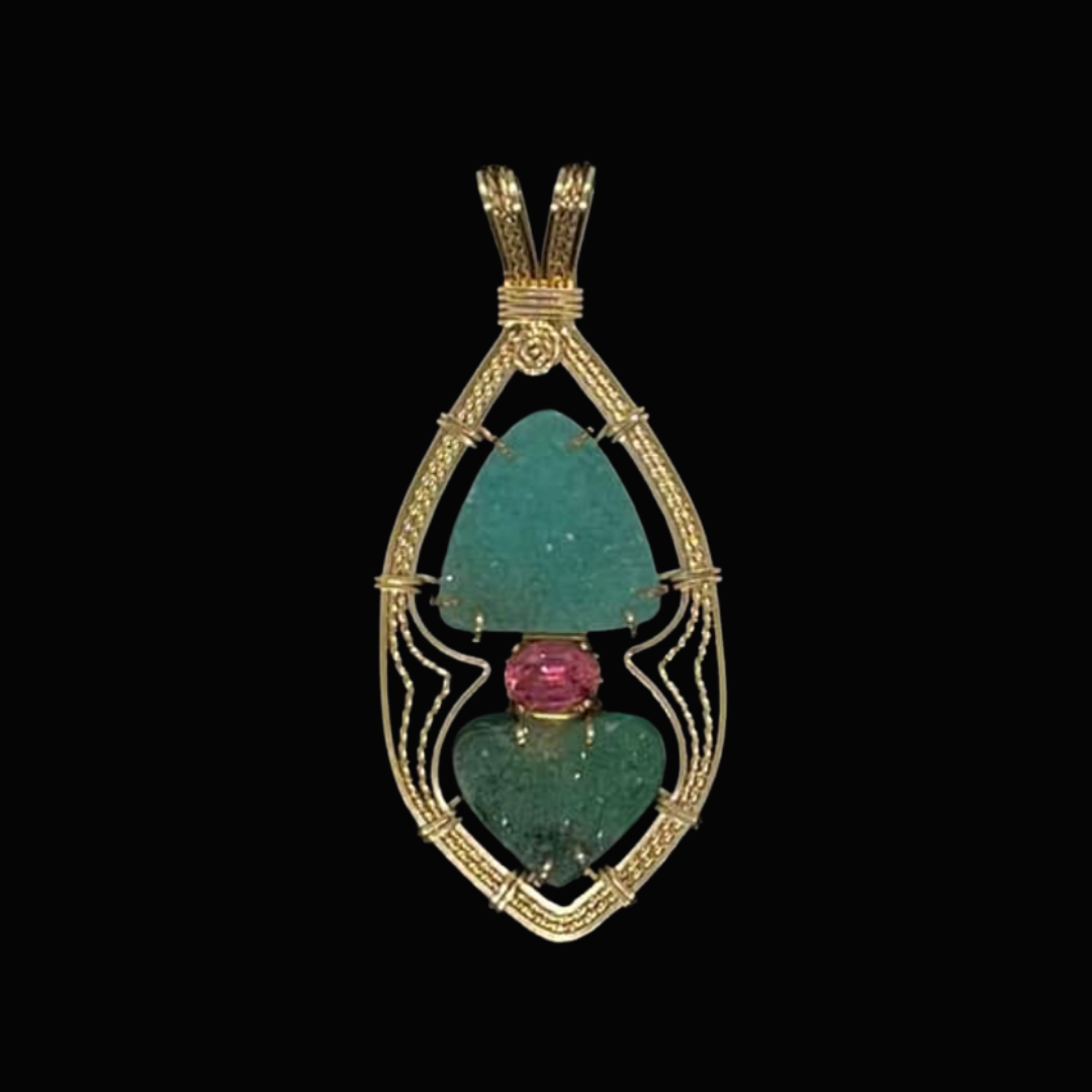 Gold pendant featuring an intricate design with green and pink gemstones against a black background.