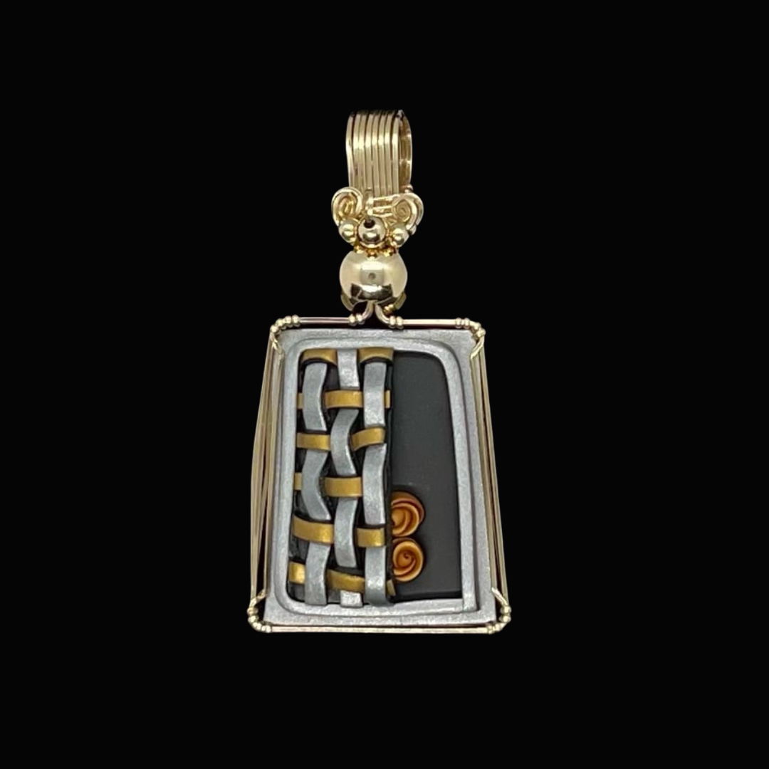 A pendant with a rectangular frame, featuring intricate gold and silver woven design on one side, and orange spiral accents on a black background inside the frame, hanging from a gold bail with decorative elements.