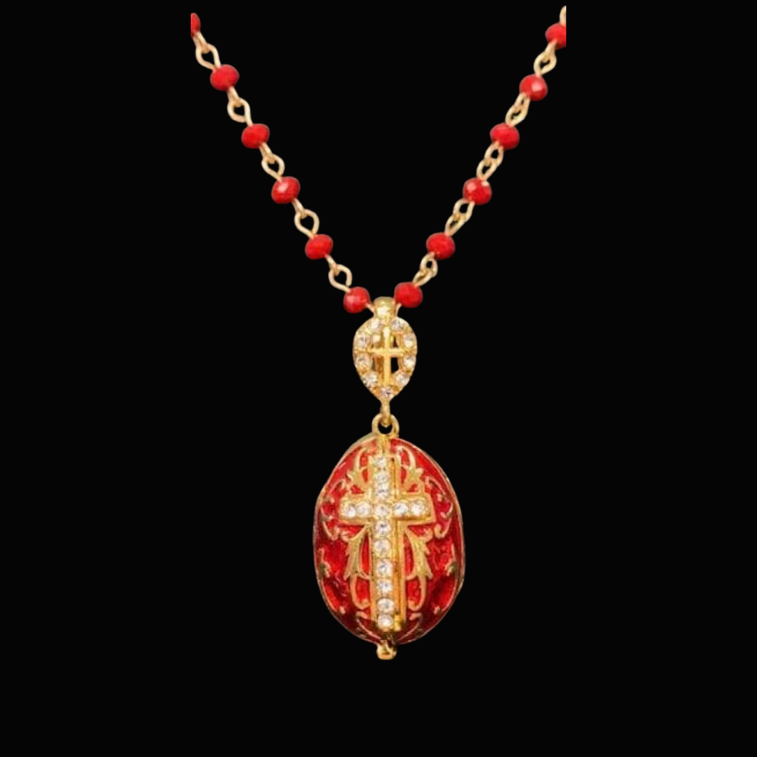 Gold necklace with red beads and two cross pendants, one encrusted with diamonds, on a black background.
