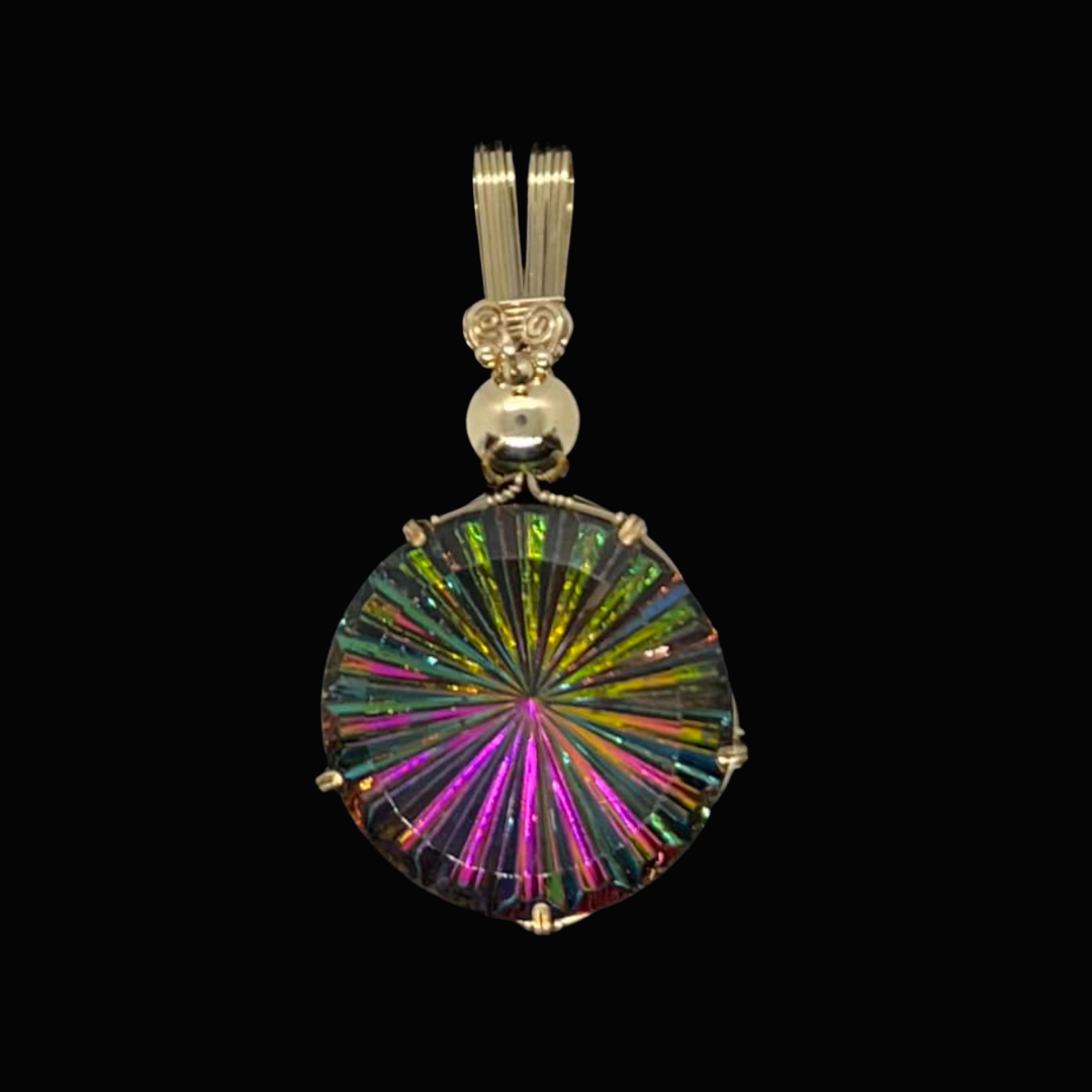 Colorful circular pendant with a radiating pattern, attached to a silver bail and decorative bead, set against a black background.