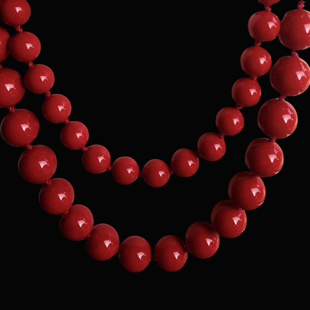 Close-up of a red beaded necklace against a black background.