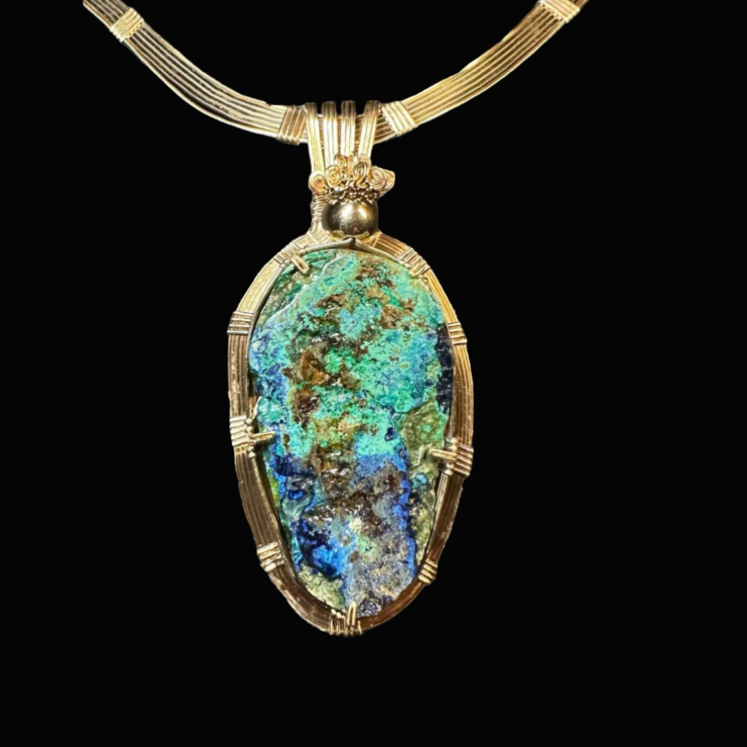 Gold necklace with a large, oval, iridescent pendant against a black background.
