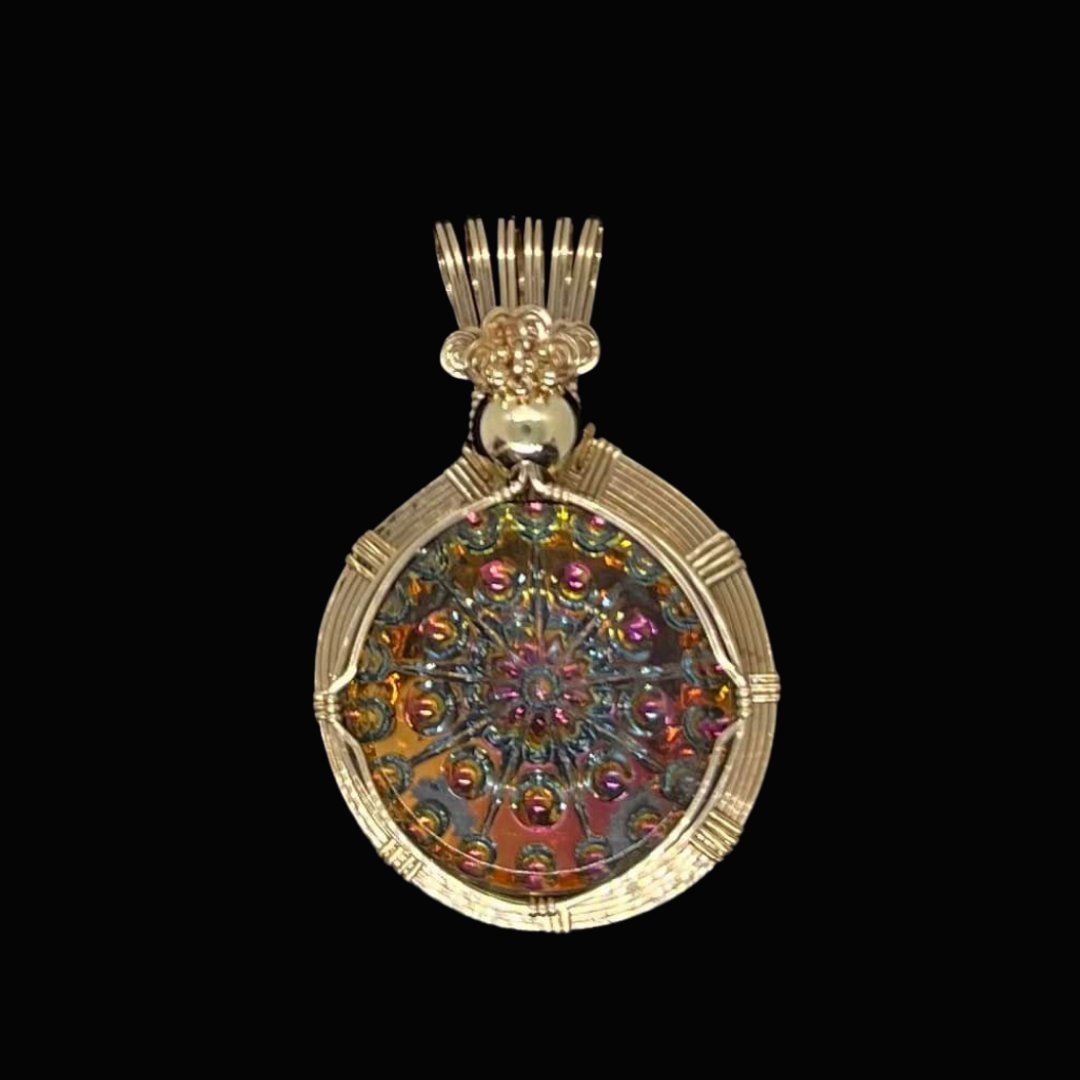 A gold pendant with an intricate, colorful, circular design, set against a black background.