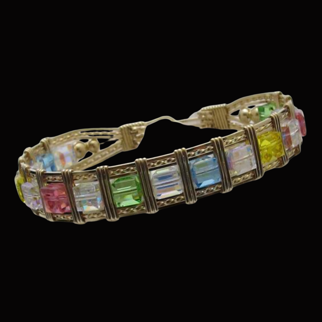 Gold bracelet with multicolored rectangular gemstones against a black background.