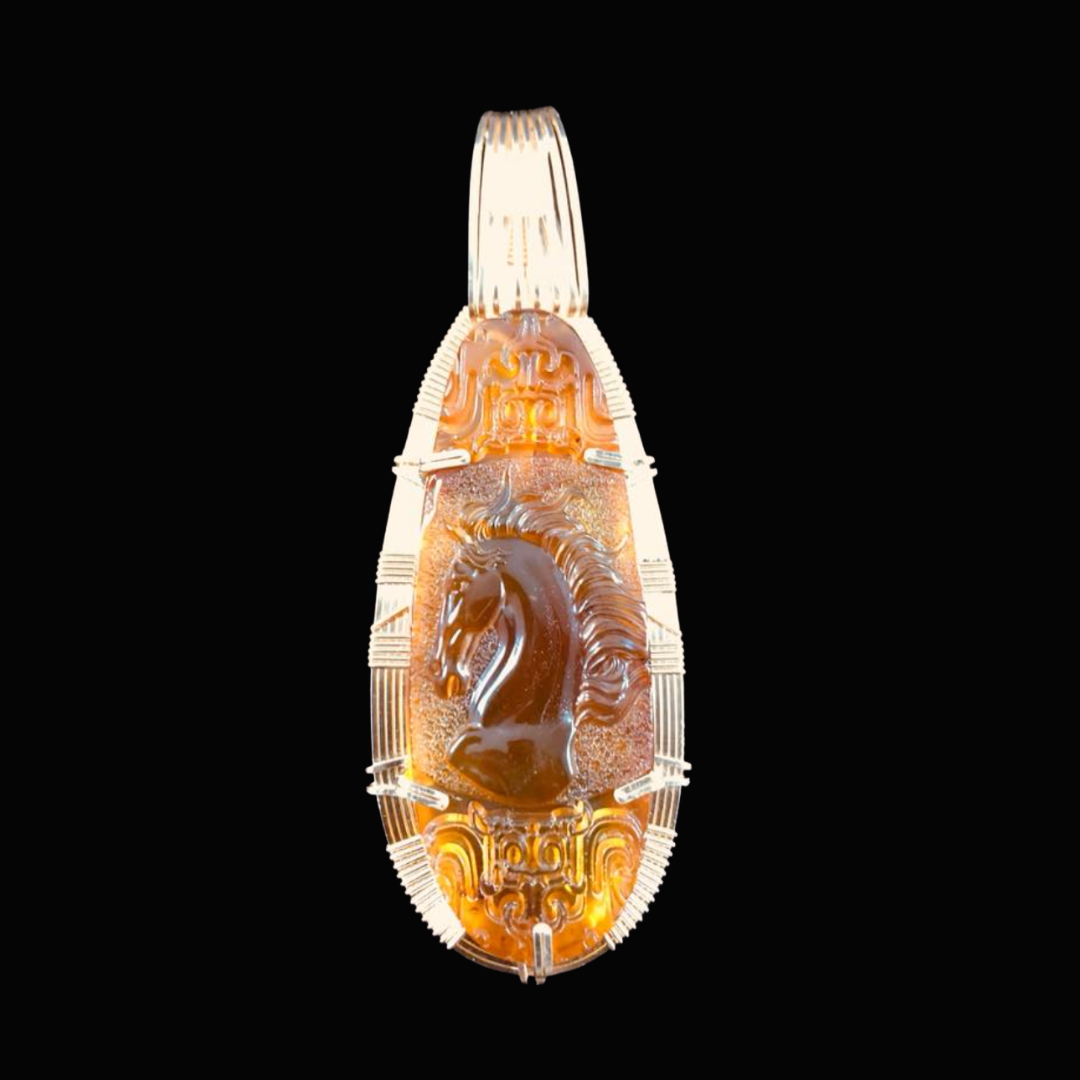 Jewelry pendant with a carved horse head design on a black background.
