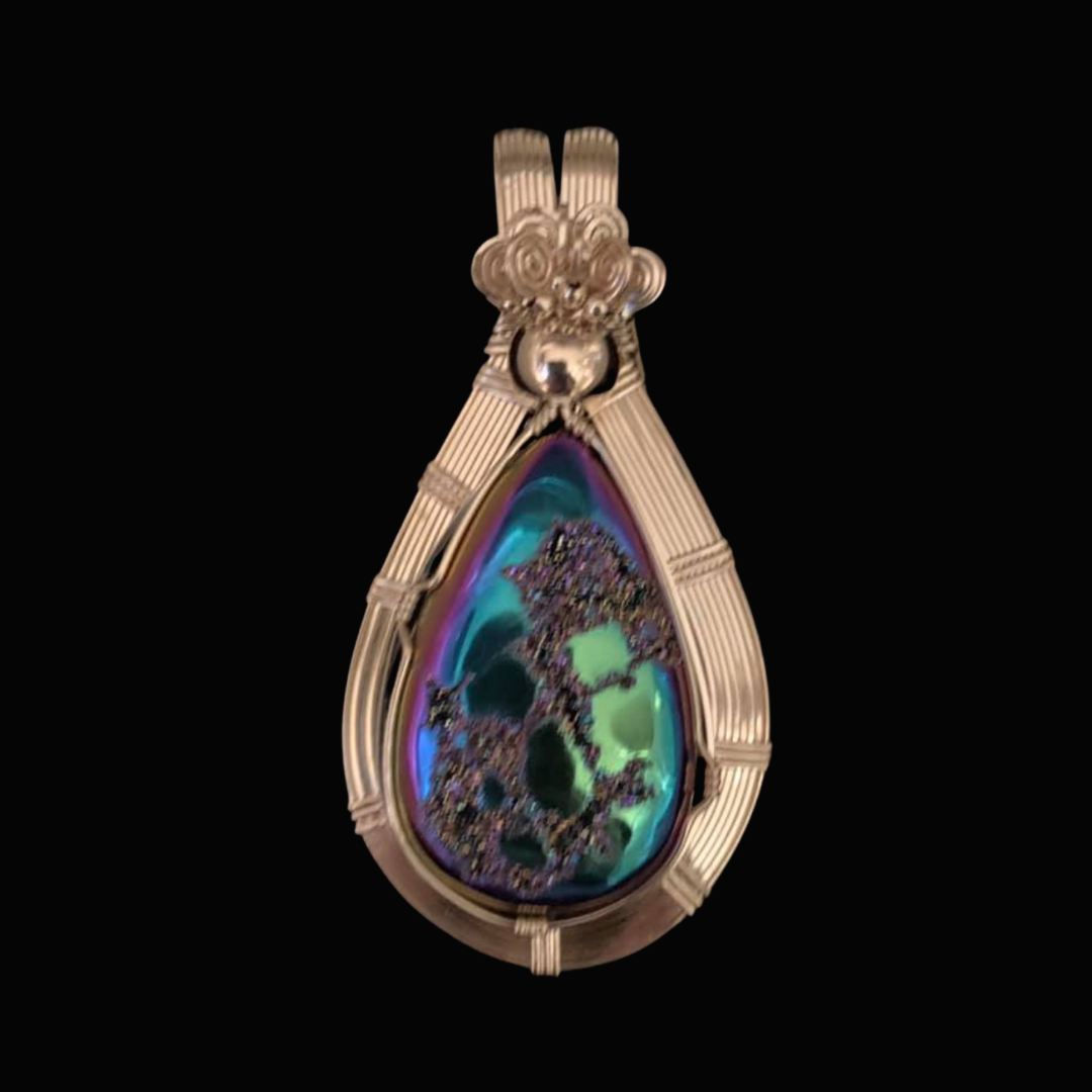 An ornate pendant with a large, colorful, iridescent teardrop-shaped gemstone set in gold with detailed gold framing and a decorative top.