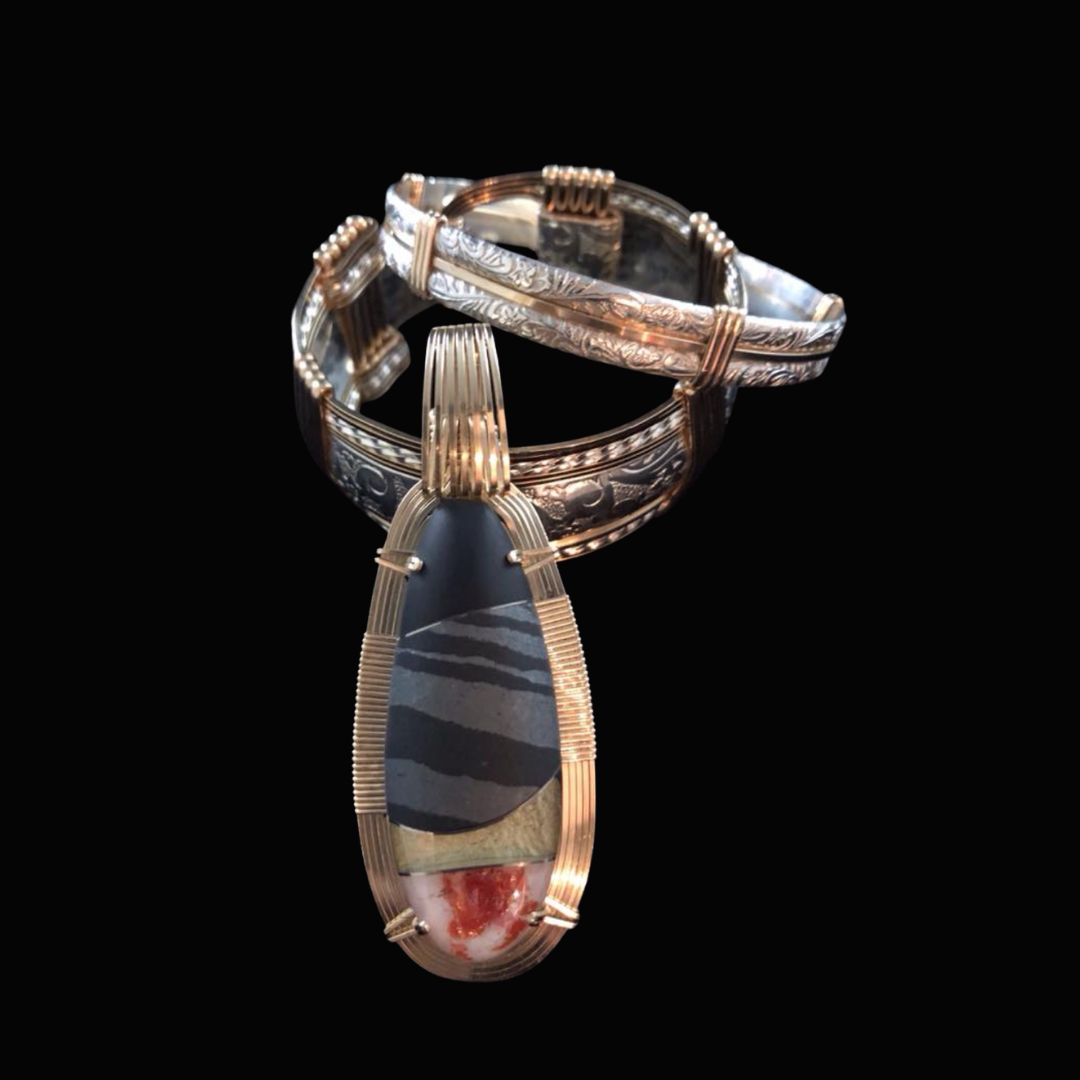 Silver and copper rings, one with a large black, white, and red stone, against a black background.