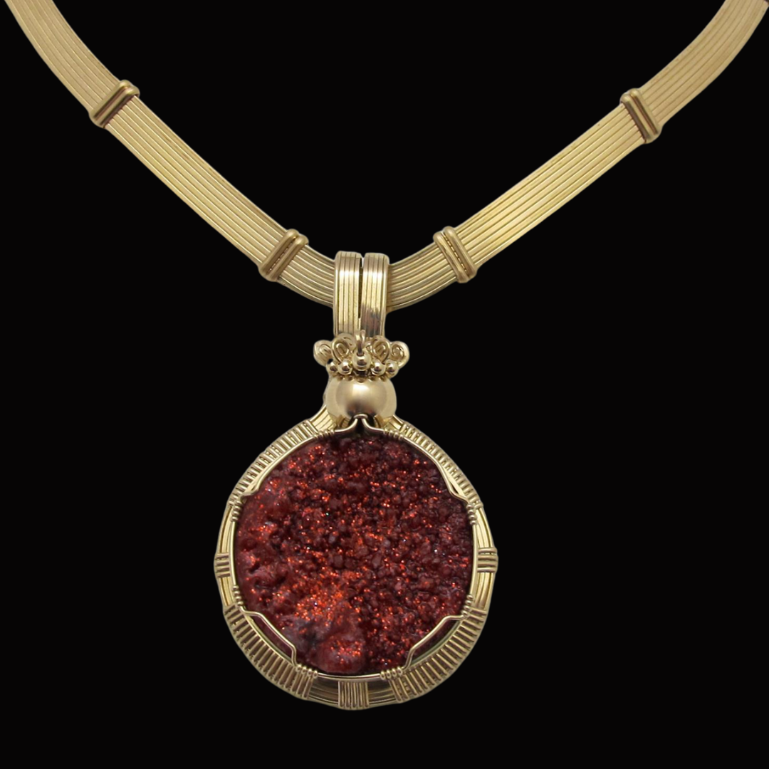 Gold necklace with a large, textured red pendant on a black background.