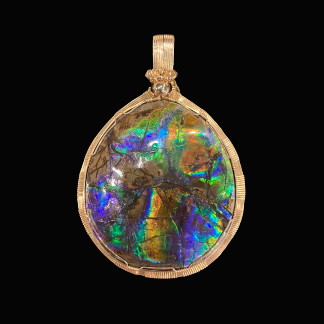 Pendant with iridescent stone and gold wire setting, against black background.