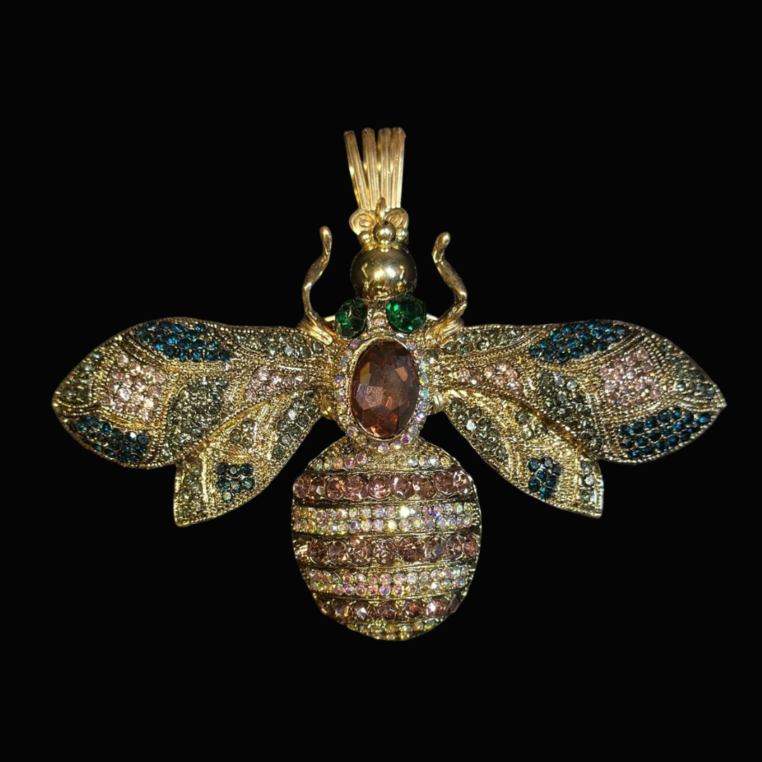 Jewelry pendant in the shape of a bee, decorated with multicolored gemstones and set against a black background.