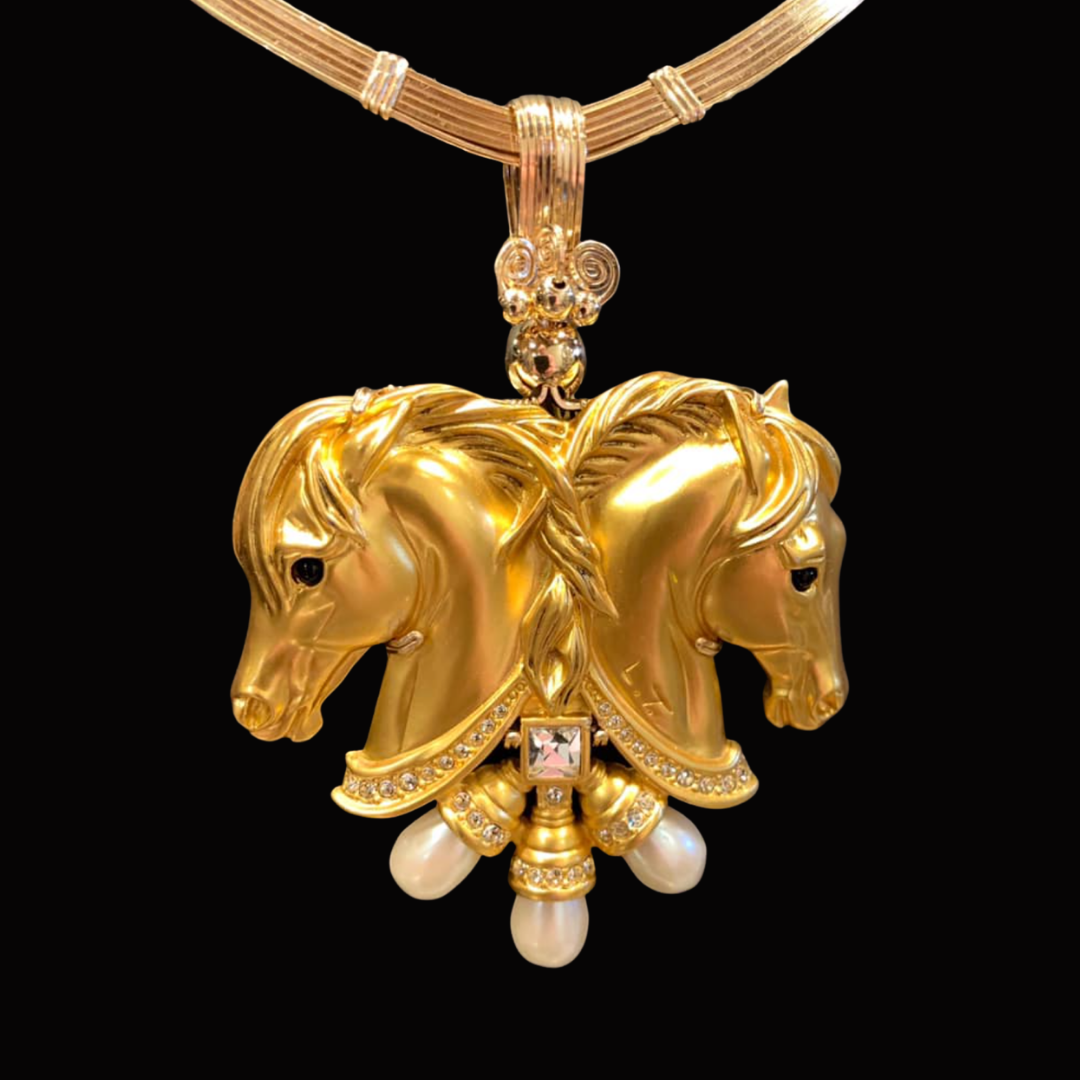 Gold necklace with a large pendant featuring two horse heads, adorned with pearls and small diamonds, with a square-cut gem and pearl drops.