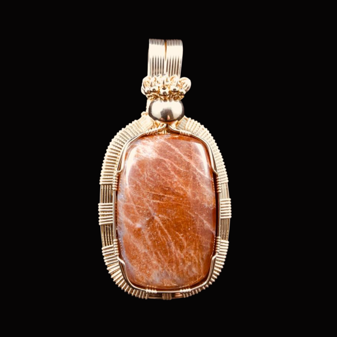 Pendant with a large oval orange stone set in a decorative silver frame, on a black background.