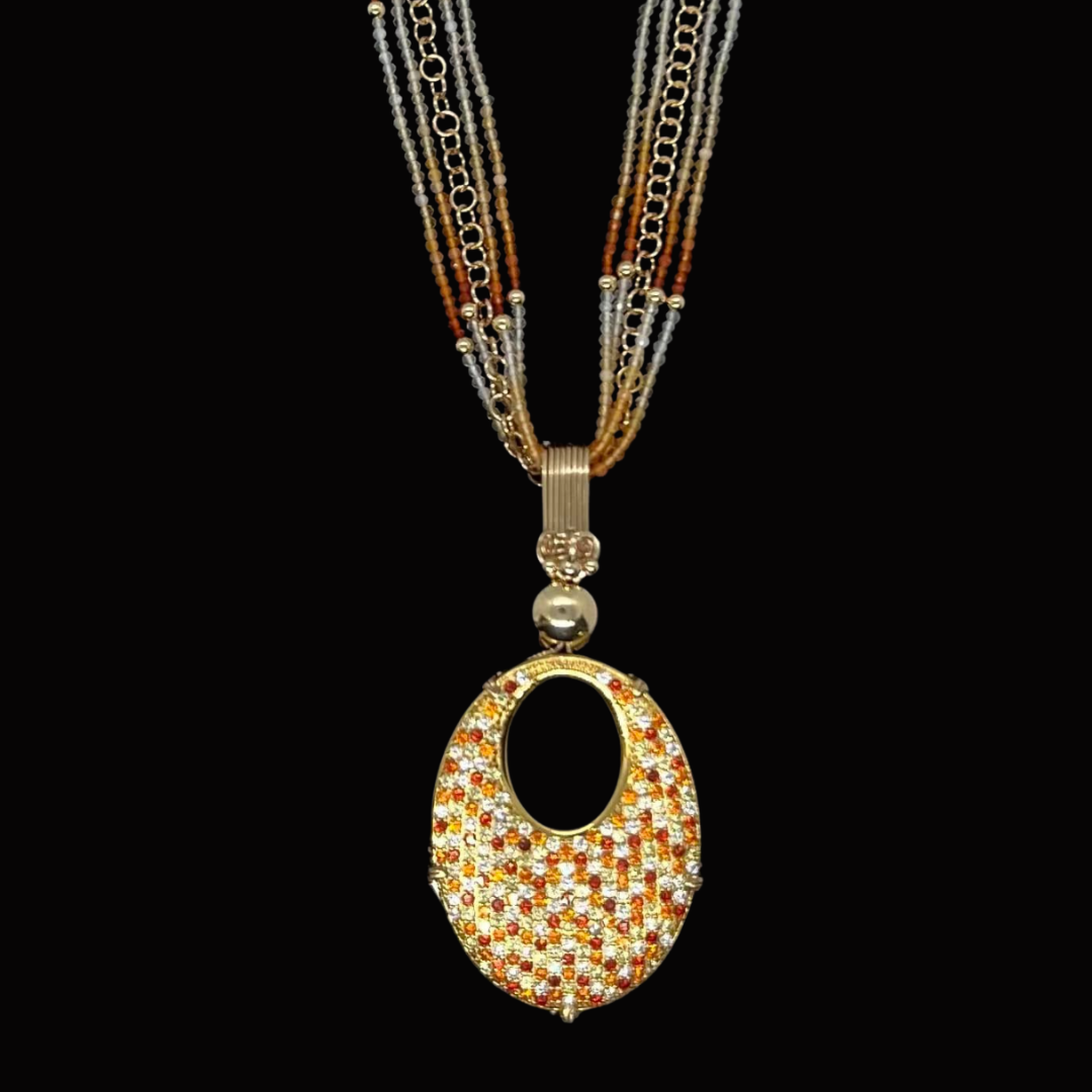 A multi-strand necklace with small beads and a large oval-shaped, jeweled pendant against a black background.