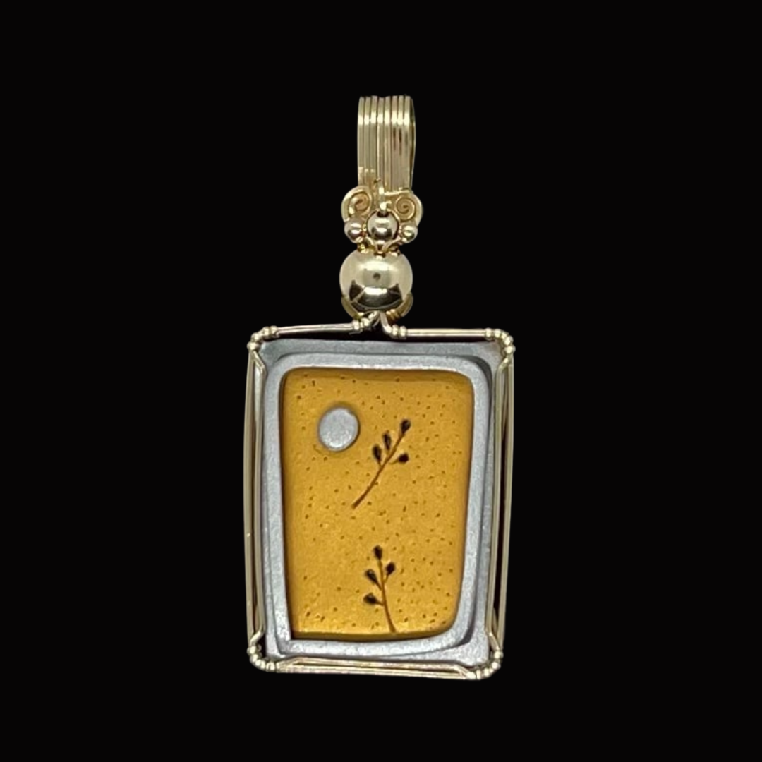 Pendant with a square frame and a yellow sponge-like background featuring small black plant illustrations, a silver dot, and a silver leaf design, mounted on a gold and silver chain.
