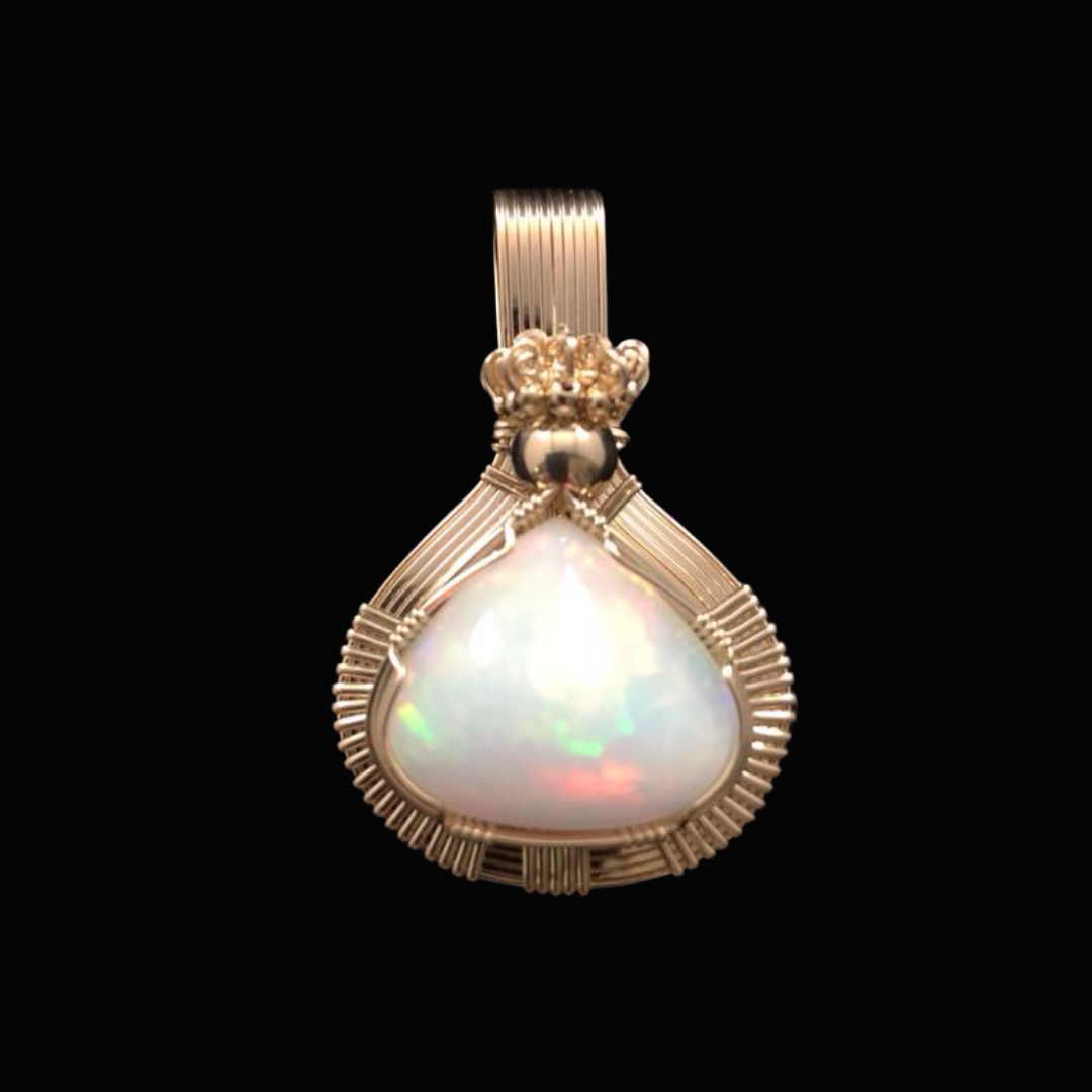 A gold pendant with a large, iridescent teardrop-shaped pearl set in the center, accented with a decorative gold crown and wire detailing, against a black background.