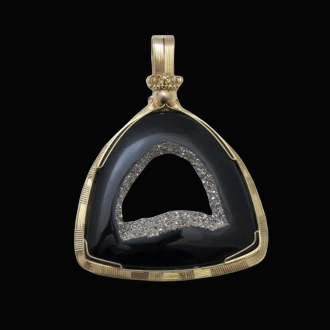 Gold pendant with black and glittery silver interior, triangular shape, against black background.