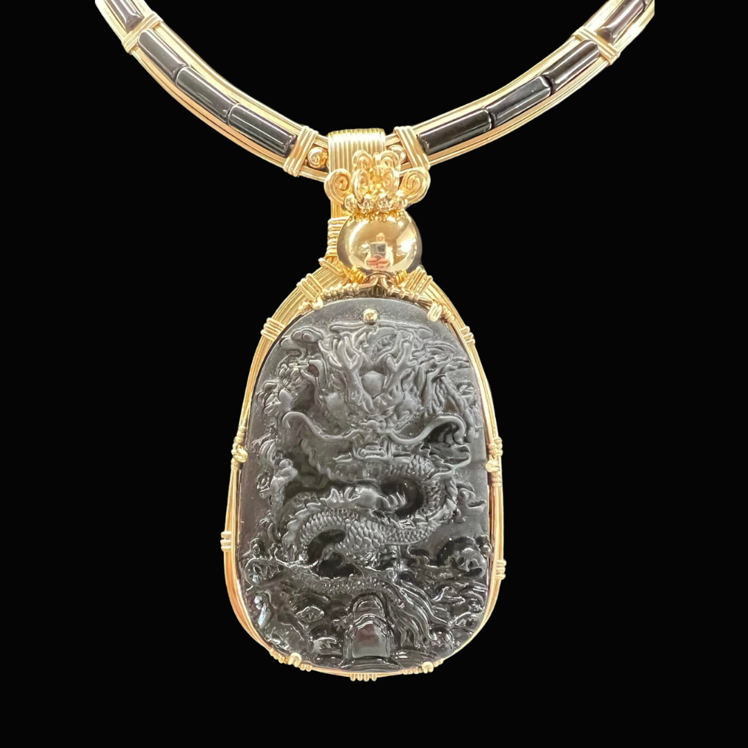 A gold and silver pendant necklace featuring a detailed dragon carving.