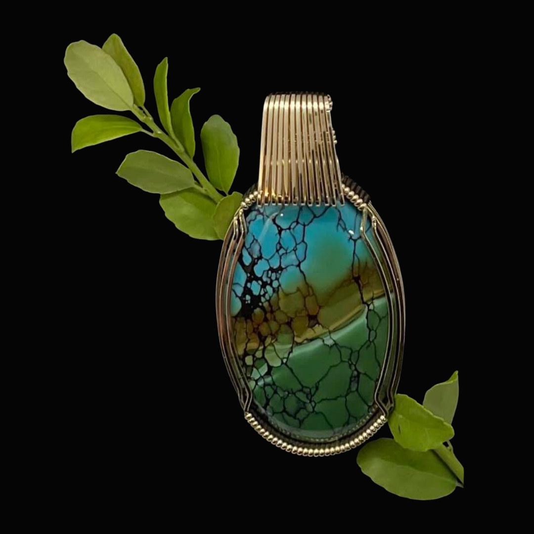 Pendant with a colorful, cracked turquoise and green stone, wrapped in metallic wire, with green leaves on a black background.