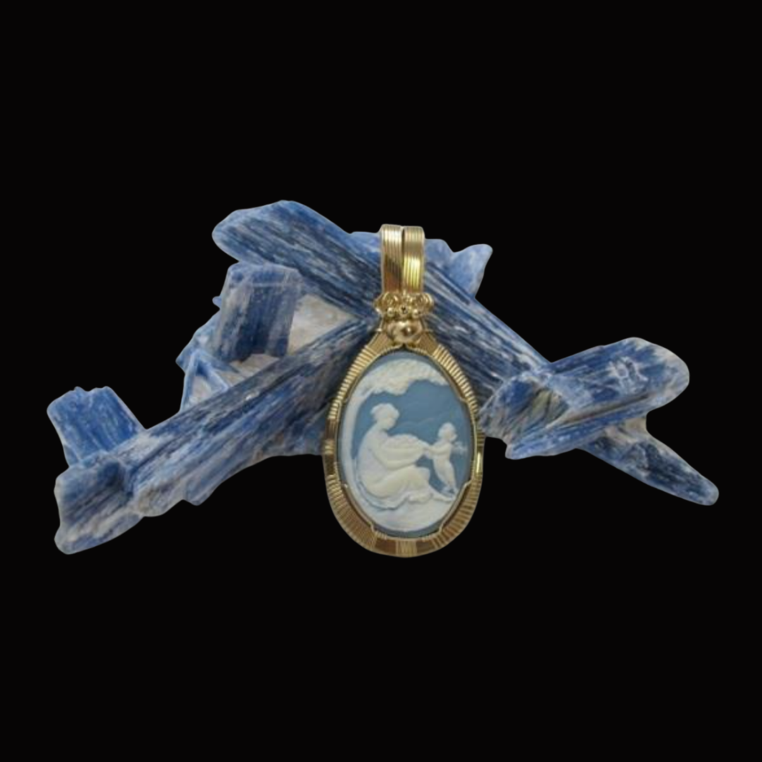 A gold pendant with an oval cameo depicting a woman with a child, resting on a large blue and white mineral specimen.