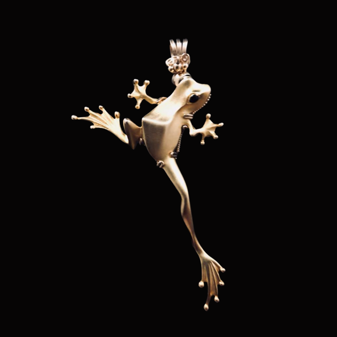 A gold frog pendant against a black background.