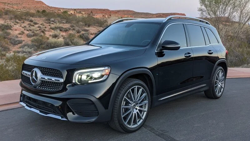 Close up of a shiny black SUV with rock rocks and sagebrush behind