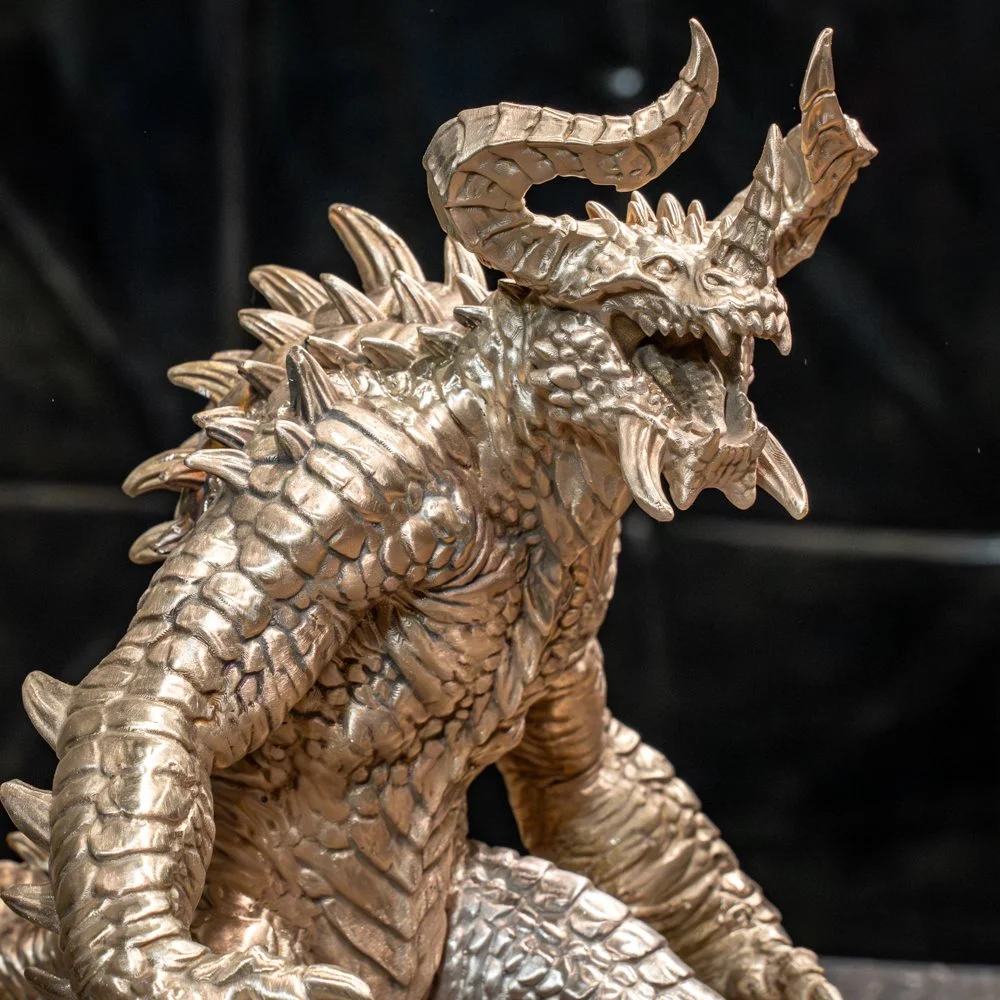 Bronze Deathclaw sculpture with large horns, spikes, and detailed scales, set against a dark background.