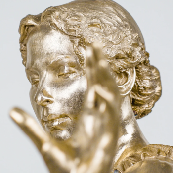 Close-up of a bronze statue of a woman with wavy hair, turned slightly to the side, with a hand in the foreground.