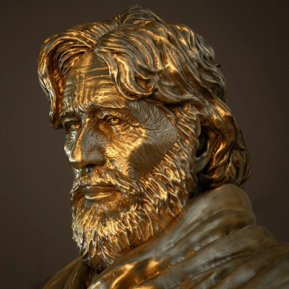 A close-up of a bronze bust sculpture of a man with a full beard and long hair, facing slightly to the side.